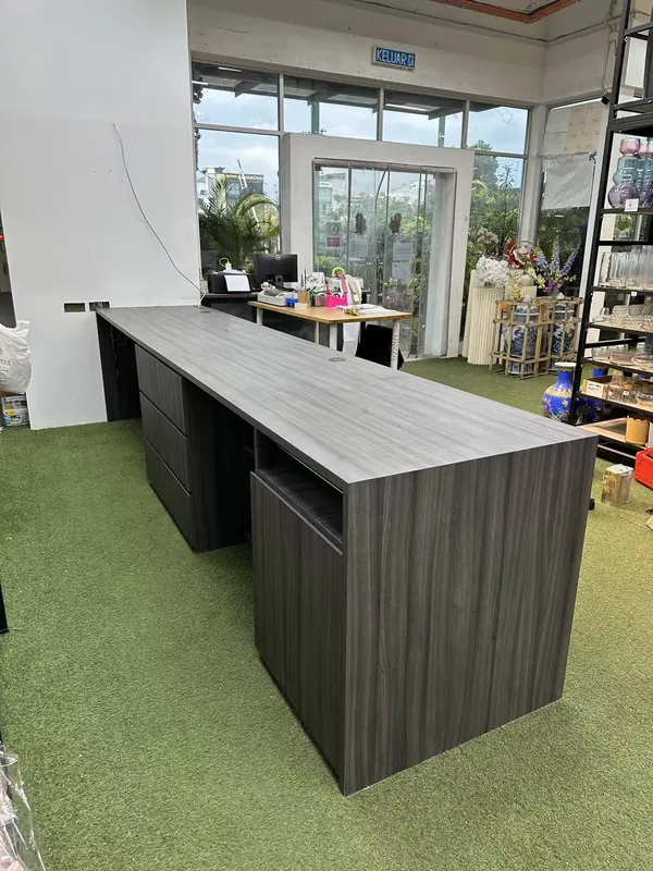 Long grey-woodgrain reception and cashier counter — commercial project, Johor Bahru