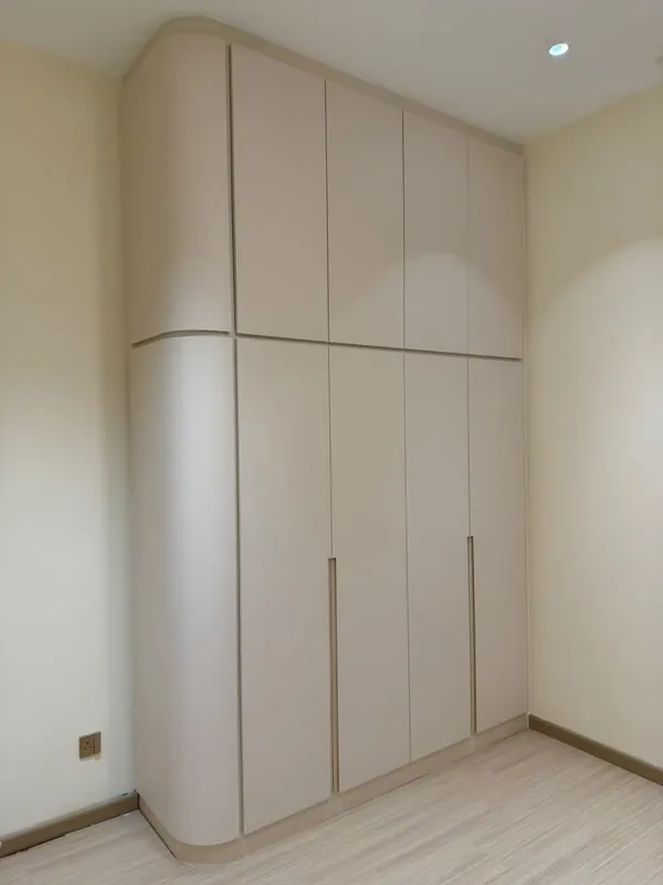 Floor-to-ceiling cream built-in wardrobe with a curved corner — Johor Bahru